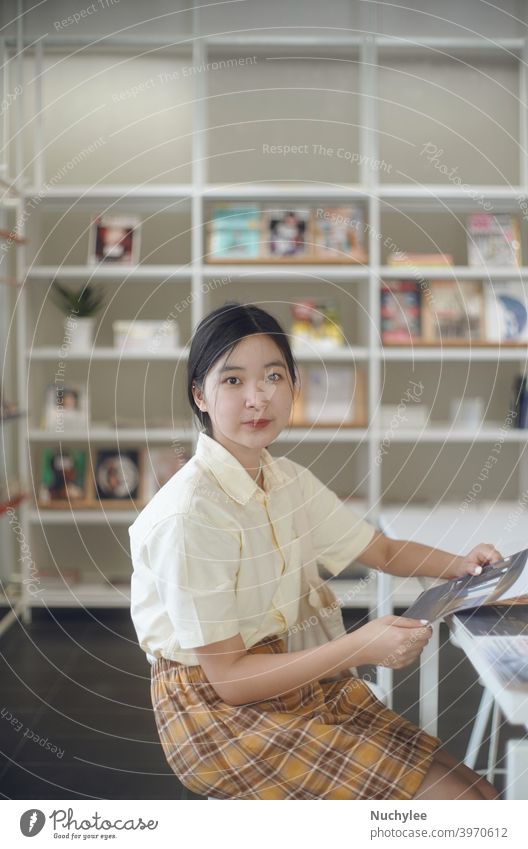 Young asian millennial teen girl in the modern library at school or campus, education and learning concept background beautiful book brunette chinese classroom