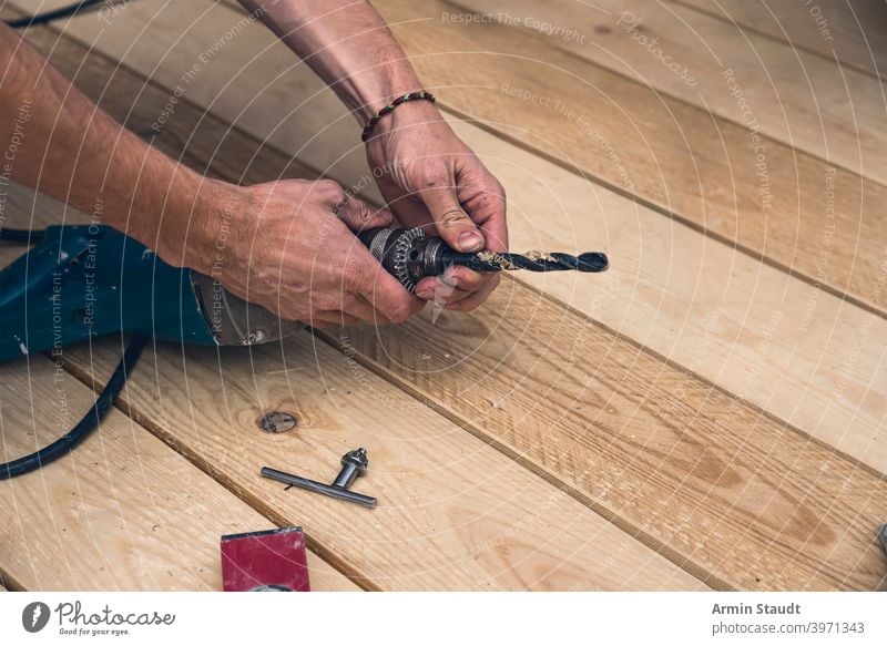 close up of a worker clamps a drill into a drill equipment machine tool man drilling power male industrial construction builder repair handyman person craftsman