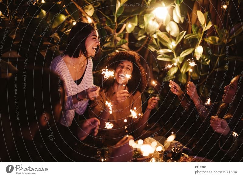 Group of friends celebrating with sparklers at garden party together 4th of july Candid Happiness People Smiling Young Adult african ethnicity backyard