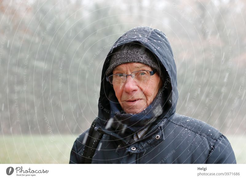 Portrait of senior standing in snow flurry with winter jacket, scarf, hat and hood Human being Man Senior citizen portrait Face Cap Scarf Hooded (clothing)