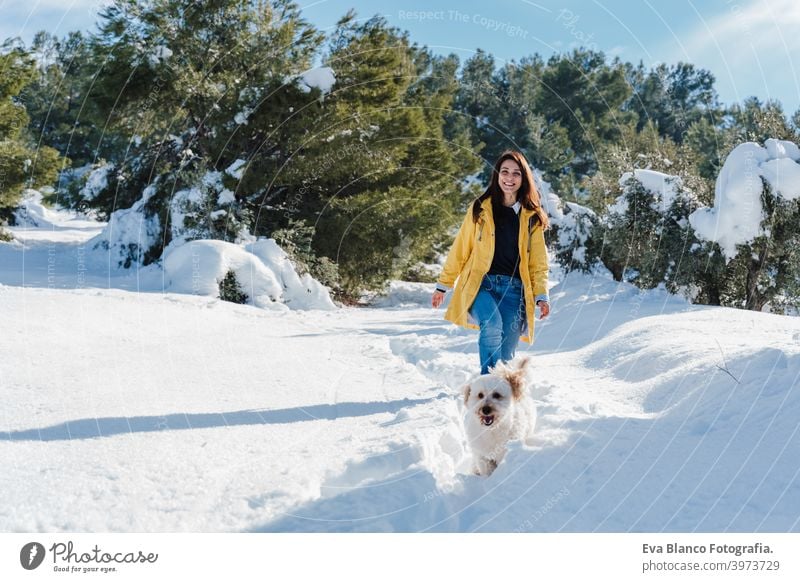 backpacker woman hiking outdoors with cute poodle dog. Snowy mountain in winter season. nature, pets and lifestyle snow yellow coat happy smiling travel daytime