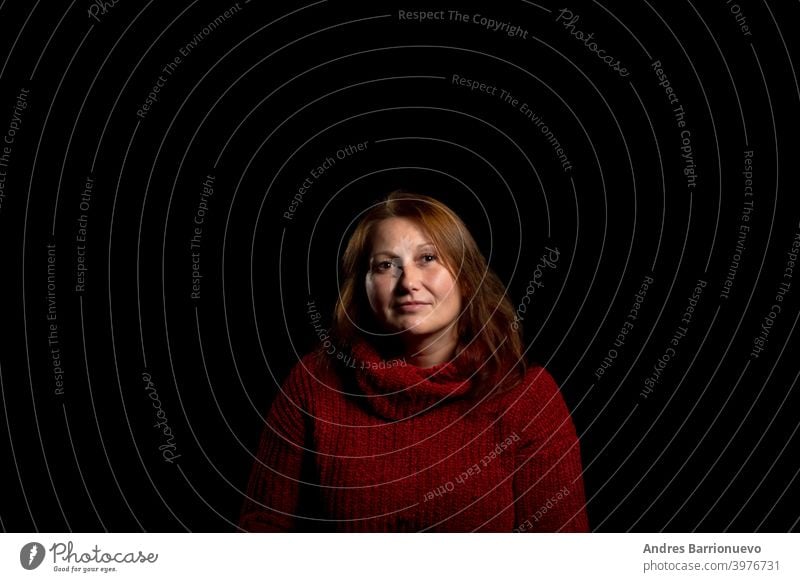 Pretty woman in a red woolen sweater posing smiling on black studio background. Copy space cute one girl agreement gesture happy casual closeup pretty portrait