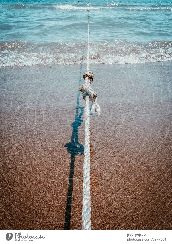 a taut rope on the beach holding up a boat Rope Beach Maritime Watercraft Dew Exterior shot Fastening coast Close-up Knot Node To hold on detaining Ocean Firm