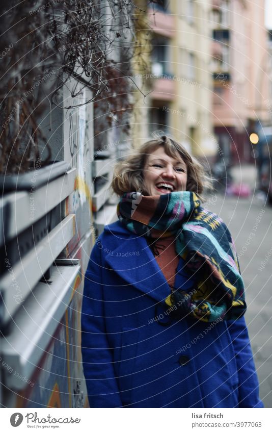 LAUGH - HAPPY - LIVE Woman Blonde Curl Winter Autumn Scarf Jacket Blue house wall Joy Joie de vivre (Vitality) Exterior shot Colour photo Happiness pretty