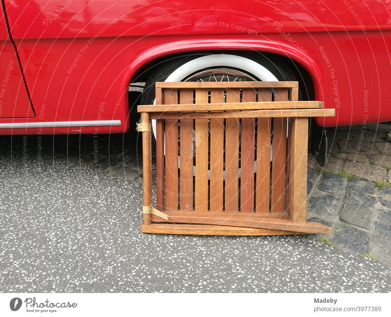 Folding table made of brown wood in front of the whitewall tire of a red convertible of the fifties at the Golden Oldies in Wettenberg Krofdorf-Gleiberg near Gießen in Hesse