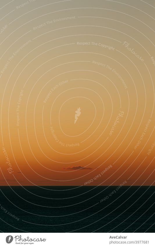 A massive horizon with an orange gradient and a single cloud with copy space and a relaxing scene minimalistic tide ocean reflection sunrise wave copy-space