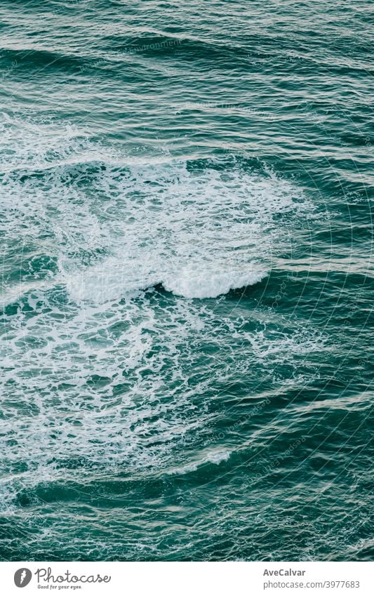 Aerial view of the ocean with the waves and re rocks during a bright day, relaxing scene on blue tones oceans copy-space meditation calmness textures peace awe