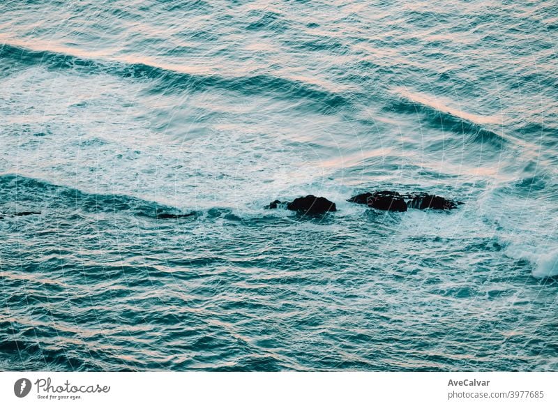 Aerial view of the ocean with the waves and re rocks during a bright day, relaxing scene on blue tones oceans copy-space meditation calmness textures peace awe