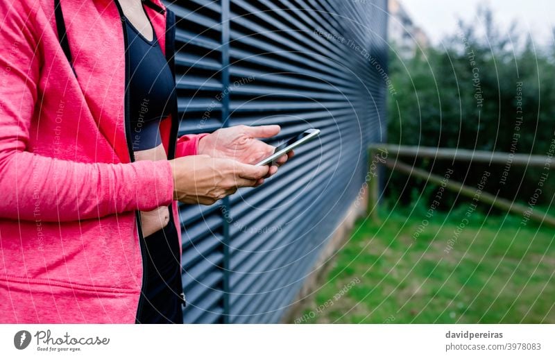 Unrecognizable female athlete with mobile phone unrecognizable woman midsection grating background cell phone profile perspective portrait body fitness hands