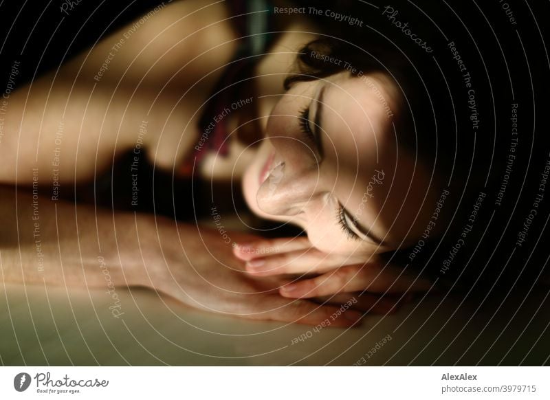 Portrait of a young woman lying with her head and arm on the table, play of light and shadow Woman naturally pretty Brunette Long-haired long hairs Slim