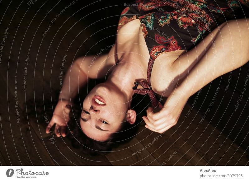 Portrait of a young brunette long haired woman lying upside down on a couch looking into the camera Woman naturally pretty Brunette Long-haired long hairs Slim