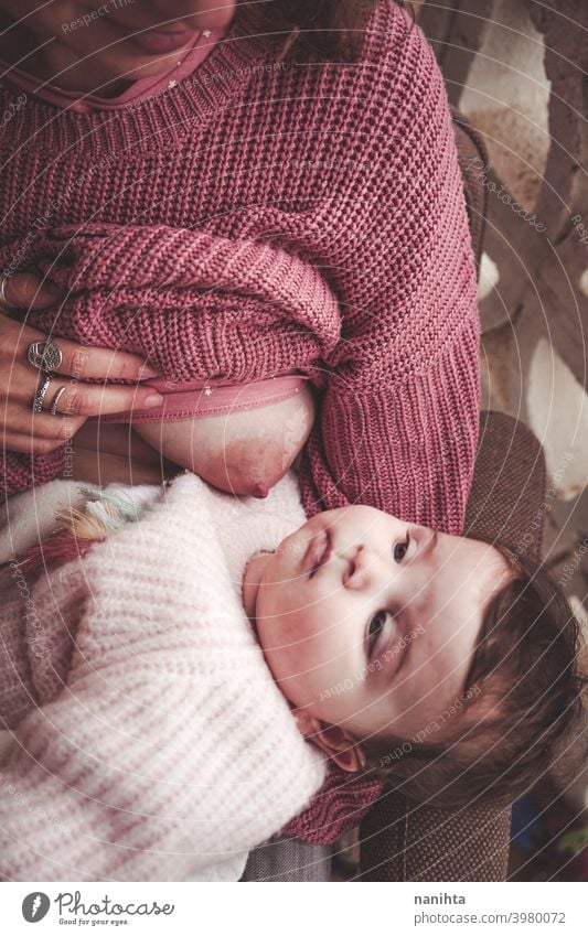 Young woman breastfeeding her baby breast feeding mom motherhood family exclusive mama infancy newborn pink warm cozy natural real life realistic love