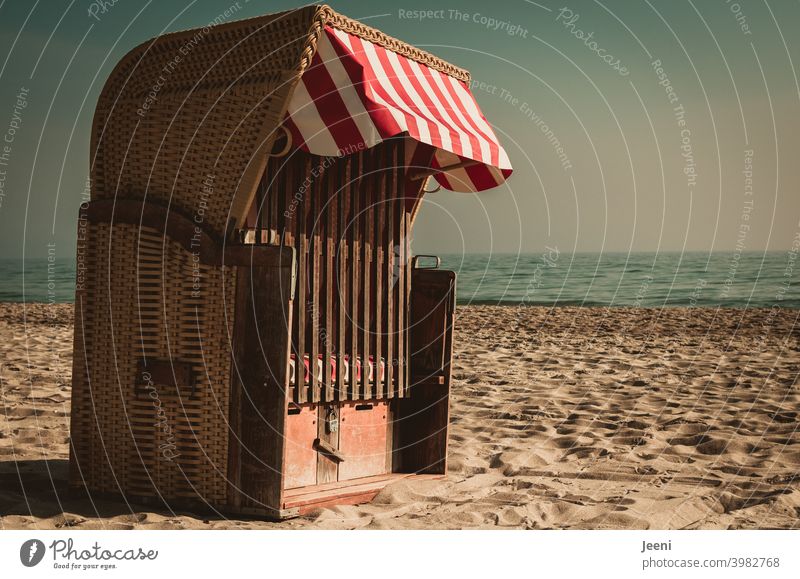 All alone and locked it stands there on the beach in the sand - the beach chair with a red and white sunshade Beach chair Ocean Sand on one's own beach sand