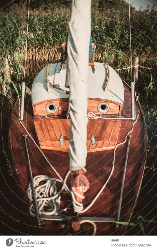 A sailboat / dinghy cruiser lies moored at the jetty and looks quite expectantly with its portholes Sailboat Wood wooden boat Sailing Navigation Sailing ship