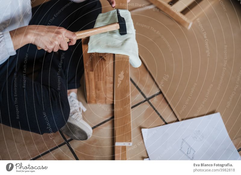 close up of young woman assembling furniture at home working with hammer. DIY concept do it yourself house caucasian indoor renovation young adult craft