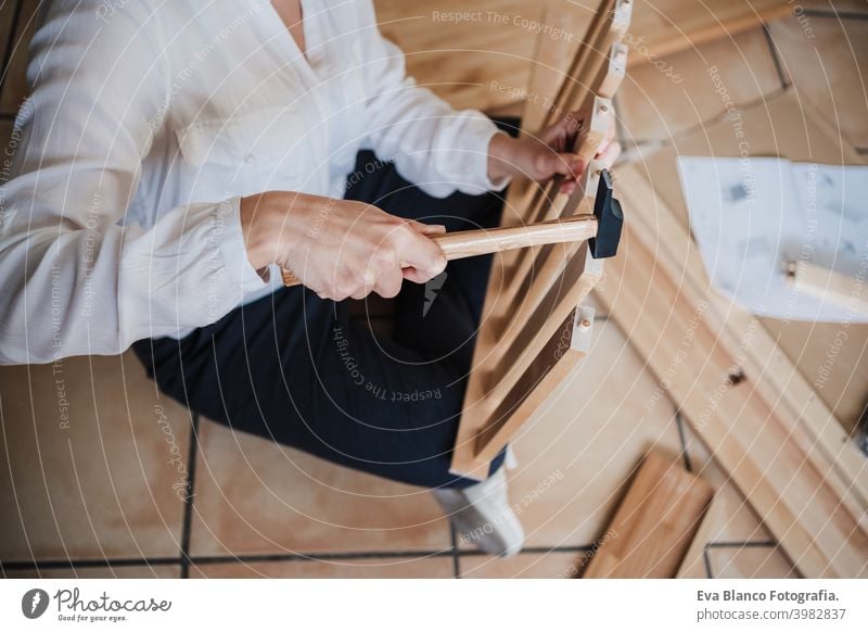 close up of young woman assembling furniture at home working with hammer. DIY concept do it yourself house caucasian indoor renovation young adult craft