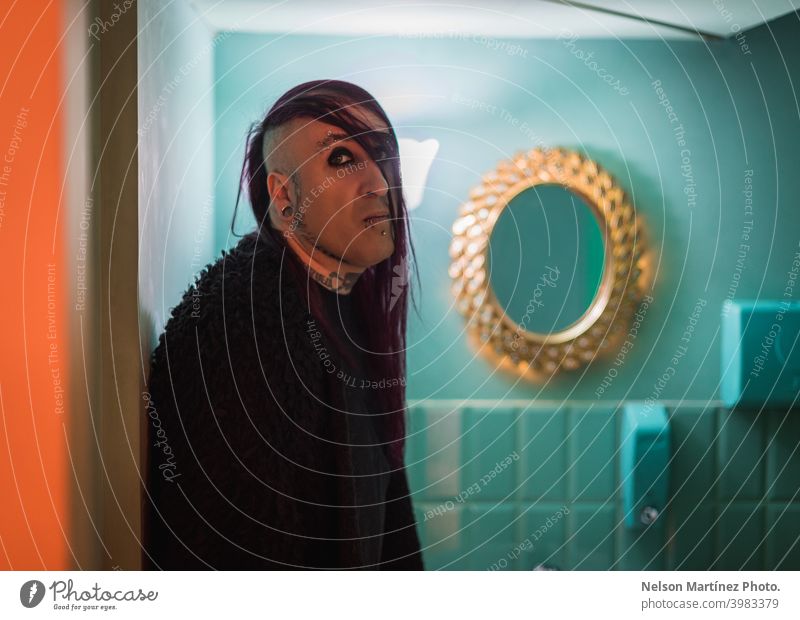 Portrait of an eccentric rocker man with long purple hair in a green bathroom. androgynous male beautiful young feminine guy closeup gay photogenic adult model