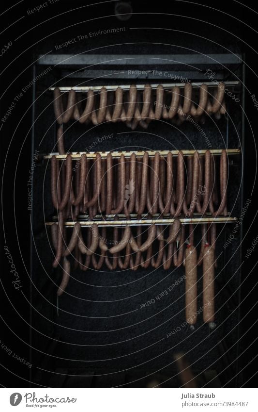 Sausage hangs on the bar in the smokehouse Butcher Fresh Smoked Nutrition Food Interior shot Meat sausage Smoked sausages spread cheesekrainer Black Dark