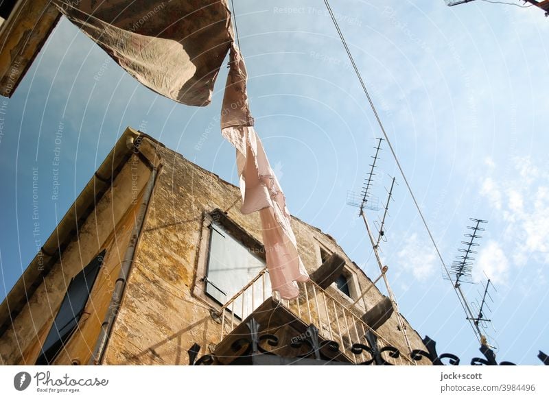 Between Greek houses, passing air extracts moisture from the laundry hanging on a clothesline, drying the clothes. Facade Greece Corfu Laundry Warmth