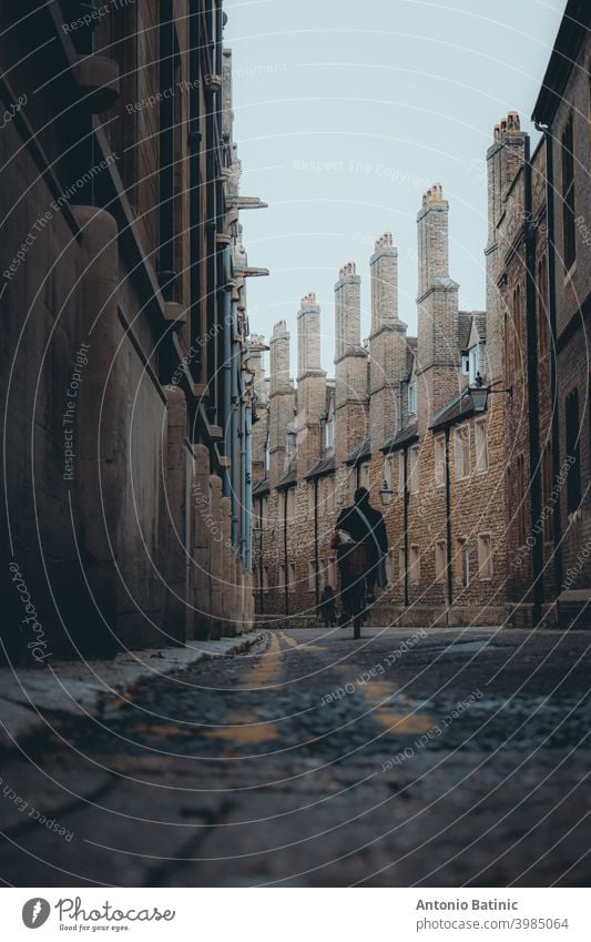 Dark moody winter atmposhere in Trinity lane, narrow famous street in the center of Cambridge city. Connecting universities, famous tourist destination spot. Person walking in the distance