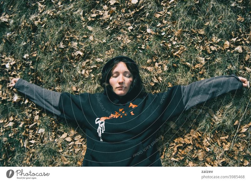 A girl with closed eyes lying down resting in nature woman lady young teen ground repose calm calmly quietness silence leaves dry dried natural zen sleep