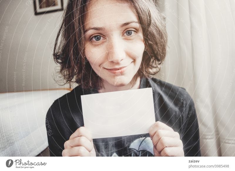 girl smiles while holding a paper with her hands people female one person indoor teen 20s 30s medium copy space center landscape horizontal color blue eyes