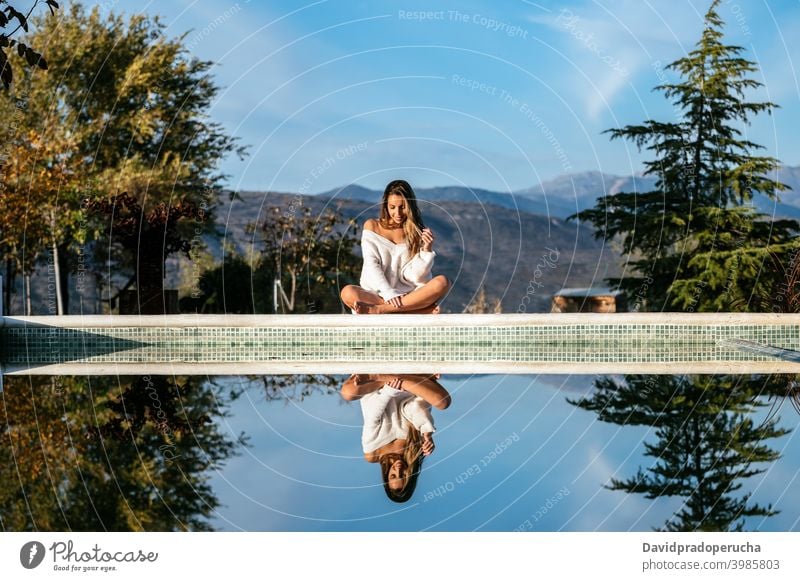 Happy woman resting in yard against mountains happy border tender smile eyes closed daytime sunny sweater positive cheerful glad joy optimist barefoot relax