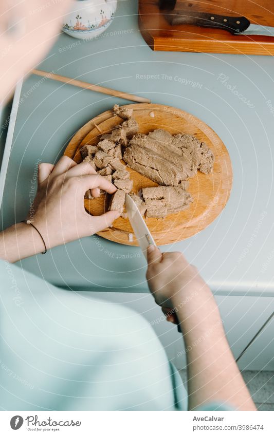 A woman cutting some tofu over a wooden round plate with a knife while cooking diner stage horizontal respect fake dining celery no one up alternative carrots