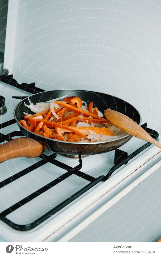 A pan filled with delicious pepper and onion while cooking in the kitchen horizontal workplace desktop person indoors asparagus inside looking variety head