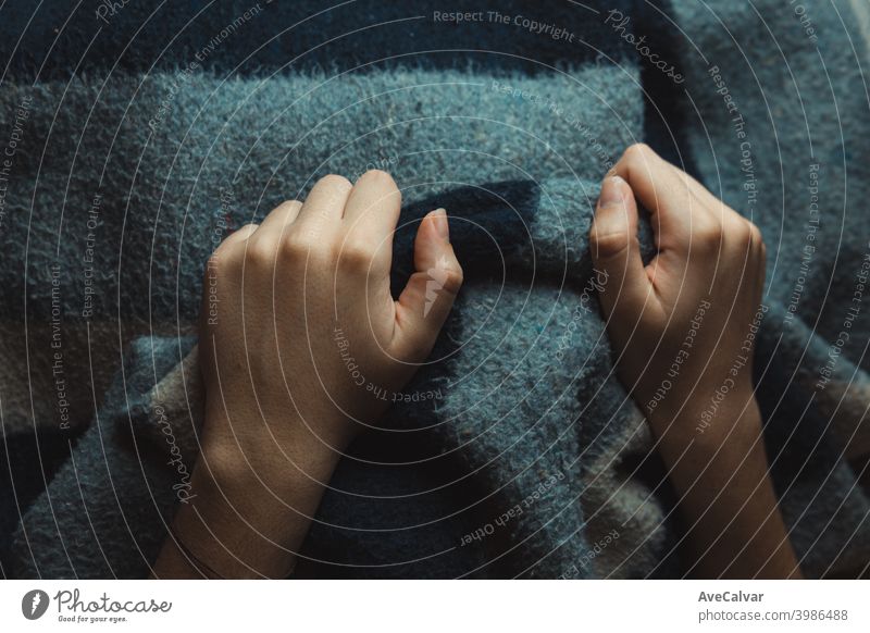 A close up of two hands holding a blue and grey blanket knee retirement patient illness relaxing males solitude horizontal loneliness usa weakness person sofa