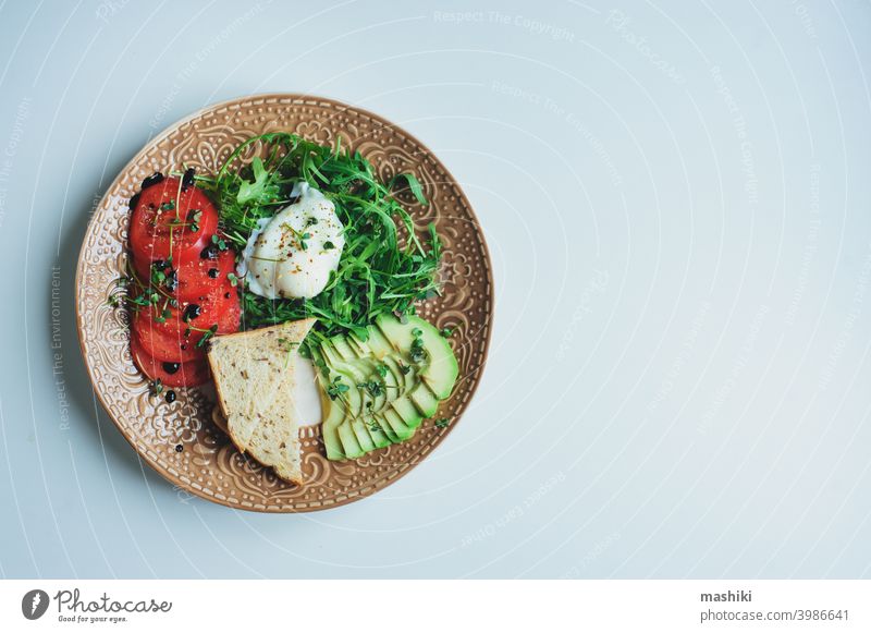 healthy diet vegetarian breakfast - poached egg, whole grain bread, tomatoes, avocado, arugula salad with olive oil and micro green vegetable food lunch meal