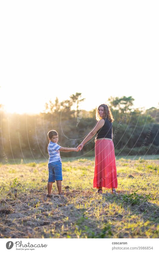 Woman and kid holding hands on a meadow autumn beautiful caucasian cheerful child childhood daughter enjoyment fall family female field forest green happiness