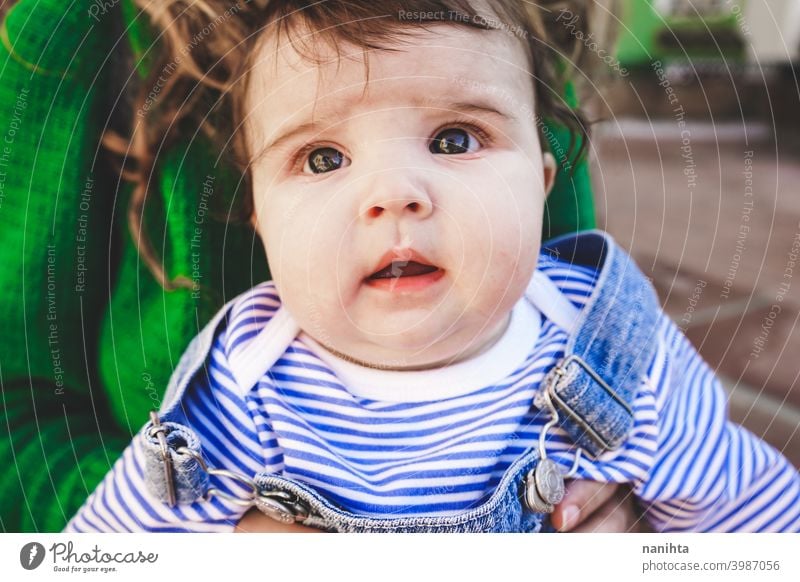 Lovely young baby in her mother arms family motherhood mom green urban long hair time trave holidays jeans casual wear young mom people real love hug