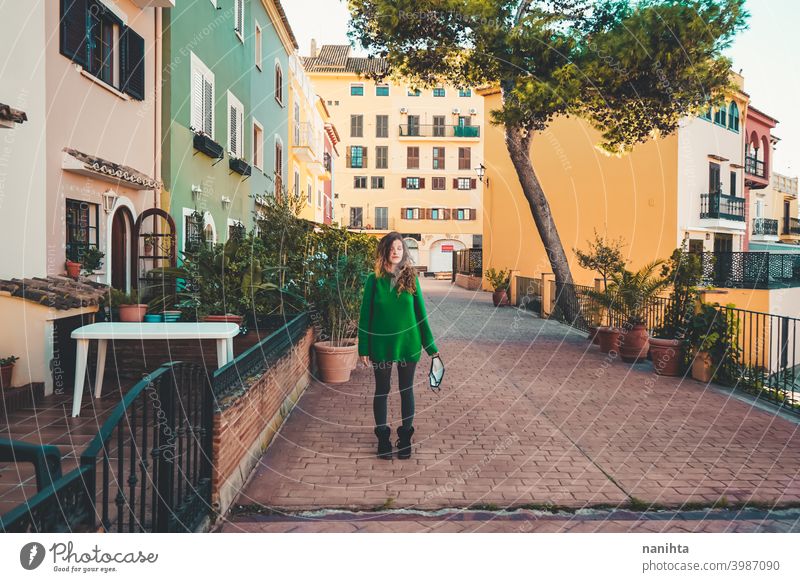 Young woman wearing green oversize sweater enjoying a windy day in a colorful city travel portrait lifestyle model europe european blonde female outdoors free