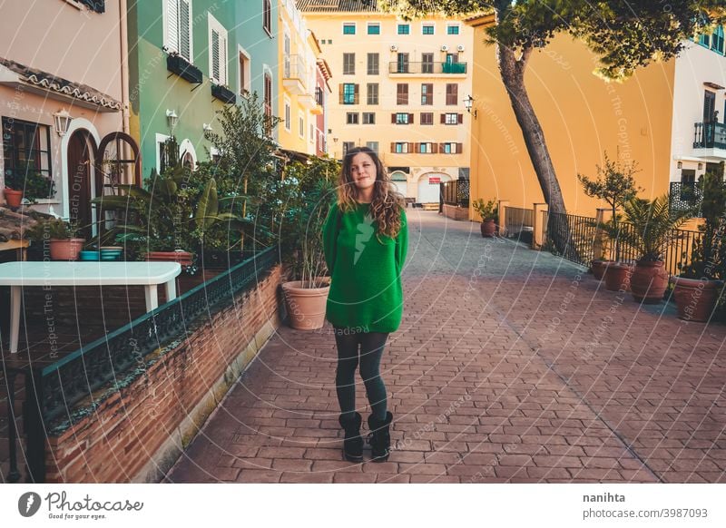 Young woman wearing green oversize sweater enjoying a windy day in a colorful city travel portrait lifestyle model europe european blonde female outdoors free