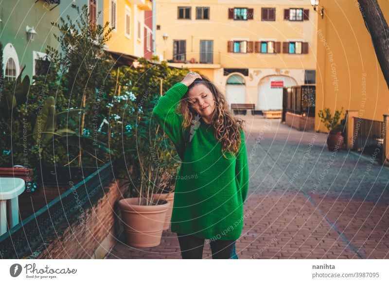 Young woman wearing green oversize sweater enjoying a windy day in a colorful city travel portrait lifestyle model europe european blonde female outdoors free