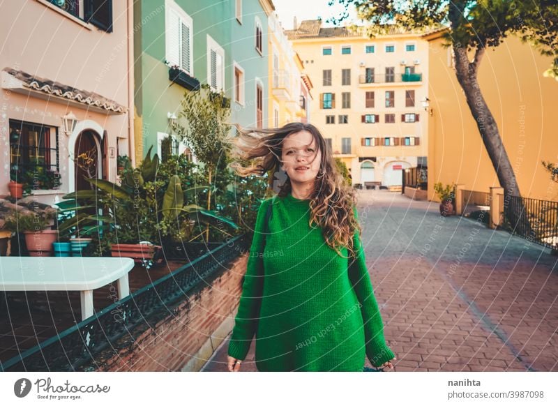 Young woman wearing green oversize sweater enjoying a windy day in a colorful city travel portrait lifestyle model europe european blonde female outdoors free