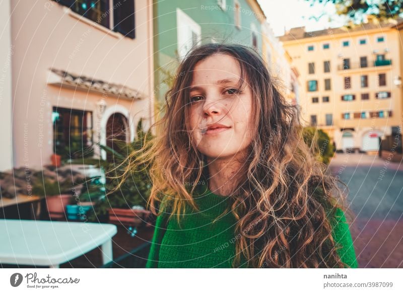 Young woman wearing green oversize sweater enjoying a windy day in a colorful city travel portrait lifestyle model europe european blonde female outdoors free