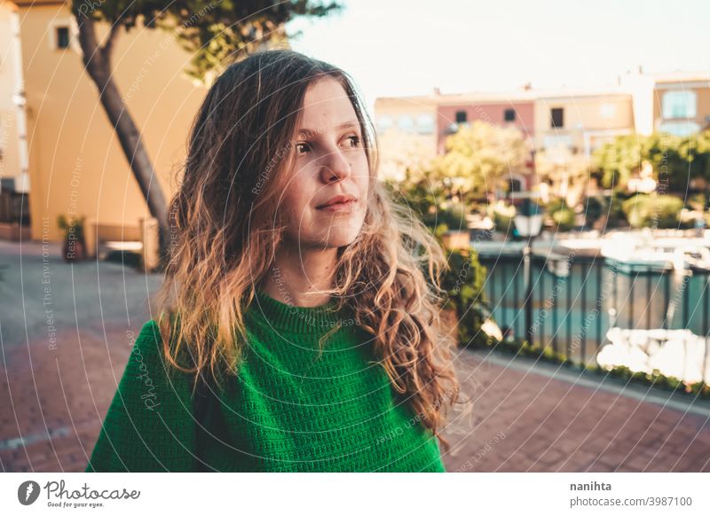 Young woman wearing green oversize sweater enjoying a windy day in a colorful city travel portrait lifestyle model europe european blonde female outdoors free