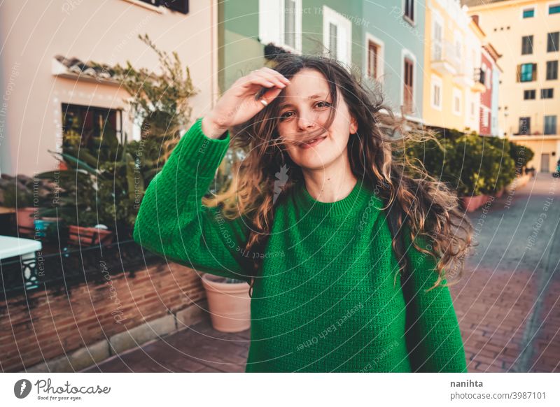 Young woman wearing green oversize sweater enjoying a windy day in a colorful city travel portrait lifestyle model europe european blonde female outdoors free