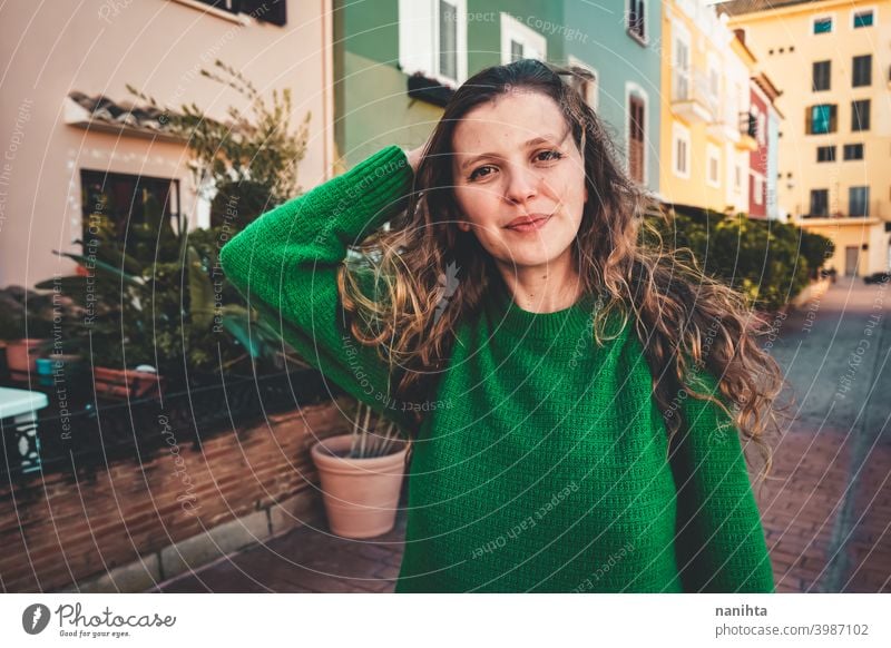 Young woman wearing green oversize sweater enjoying a windy day in a colorful city travel portrait lifestyle model europe european blonde female outdoors free