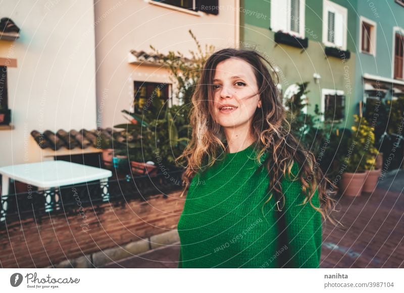 Young woman wearing green oversize sweater enjoying a windy day in a colorful city travel portrait lifestyle model europe european blonde female outdoors free