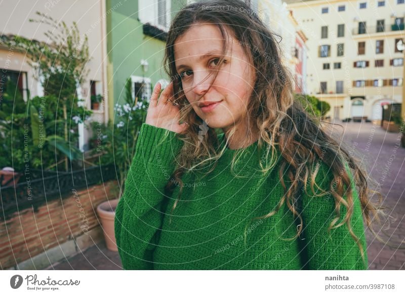 Young woman wearing green oversize sweater enjoying a windy day in a colorful city travel portrait lifestyle model europe european blonde female outdoors free