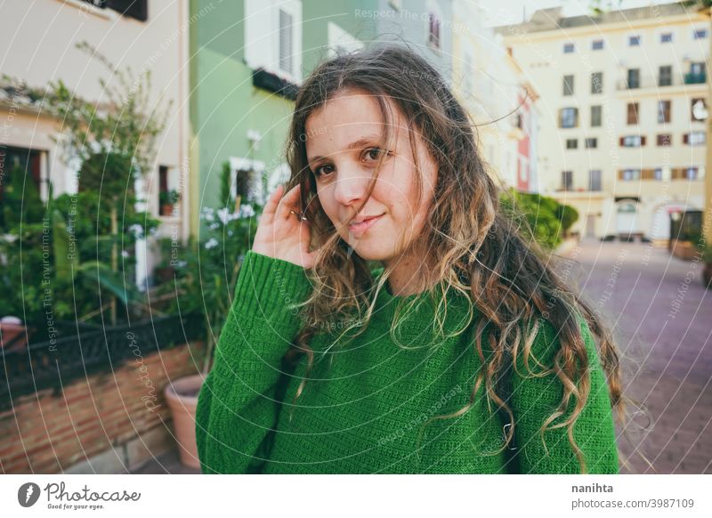 Young woman wearing green oversize sweater enjoying a windy day in a colorful city travel portrait lifestyle model europe european blonde female outdoors free