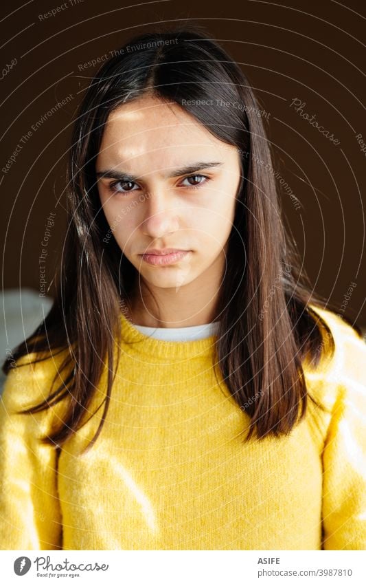 Portrait of an unhappy and displeased teen girl with a yellow sweater teenager angry upset serious portrait grumpy grouchy stress annoyed frustrated looking sad