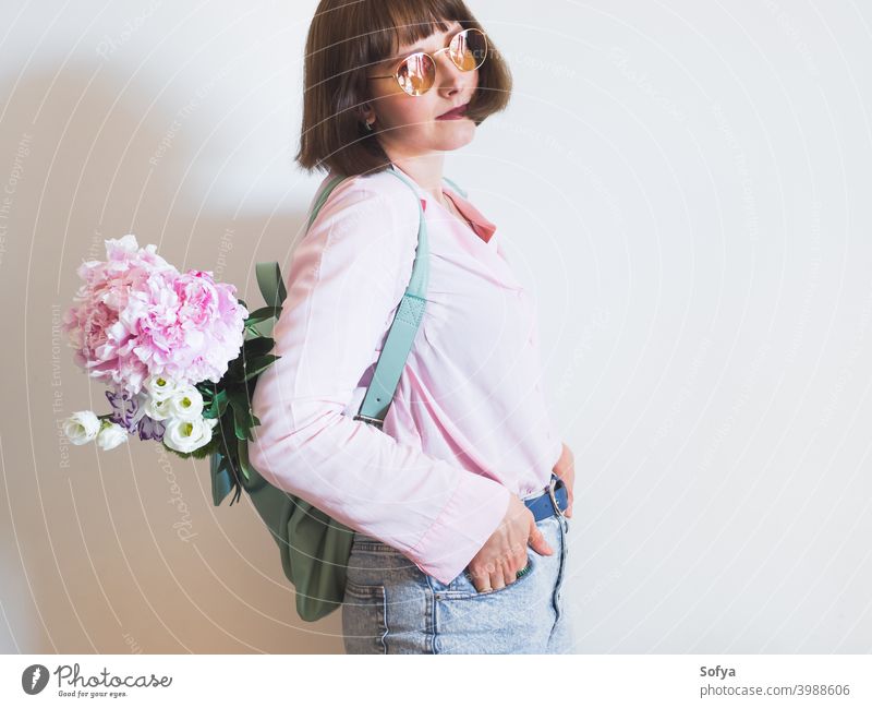 Young woman in pink with backpack and peony bouquet mother spring day authentic mothers day flowers face lifestyle womens day smile pastel expression concept