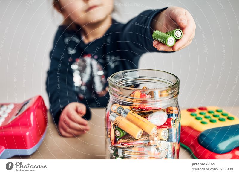 Little girl putting used batteries into jar for recycling. Child separating waste person environmental conceptual responsibility power recycle save throw