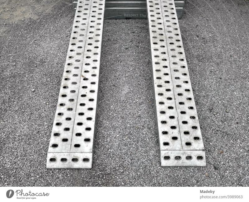 Ramp made of perforated plate of a car trailer for transporting small construction machinery on grey gravel in Helpup near Oerlinghausen in the Teutoburg Forest in East Westphalia-Lippe, Germany