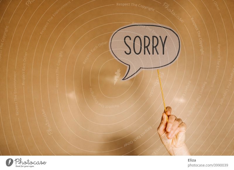 One hand holds a speech bubble in which the word Sorry is written. Sorry. Apology sorry apologize Characters Remorse repent Guilty Communicate Hand