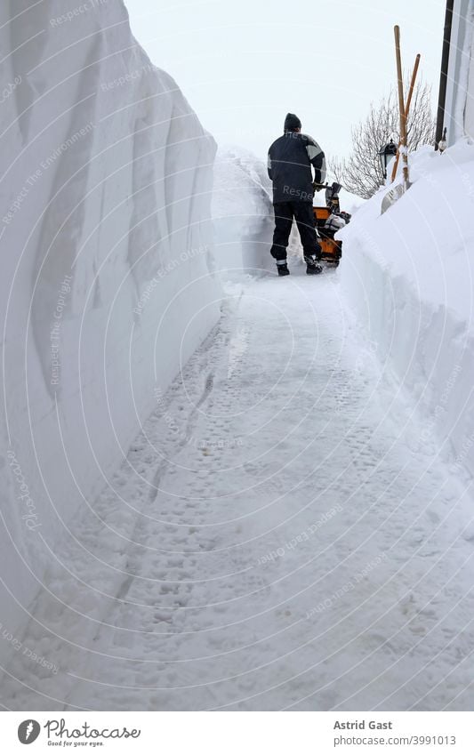 A man in Bavaria clears the pavement with a snow blower during heavy snowfall snowplough snow blowers Man Snow Winter clearance snow shovels